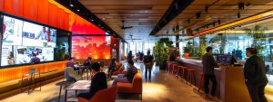 a dynamic urban office setting showcases a group of professionals collaborating around a digital display, highlighting innovative strategies for local search optimisation and community engagement.