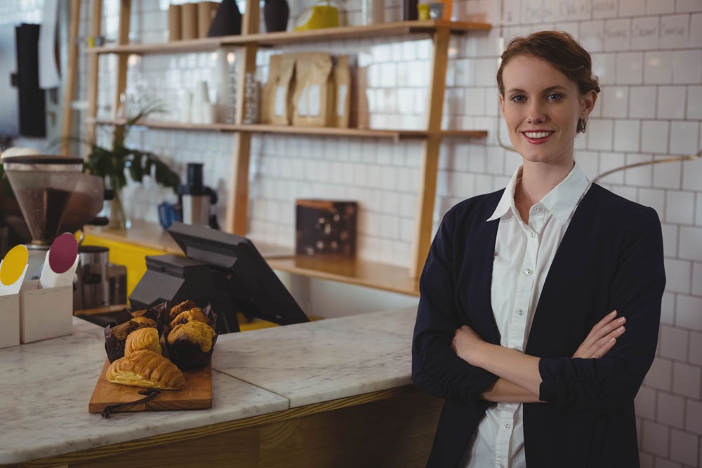 Barista smiling at a café counter with pastries, showcasing a welcoming atmosphere for local businesses in Northern Rivers and Melbourne.
