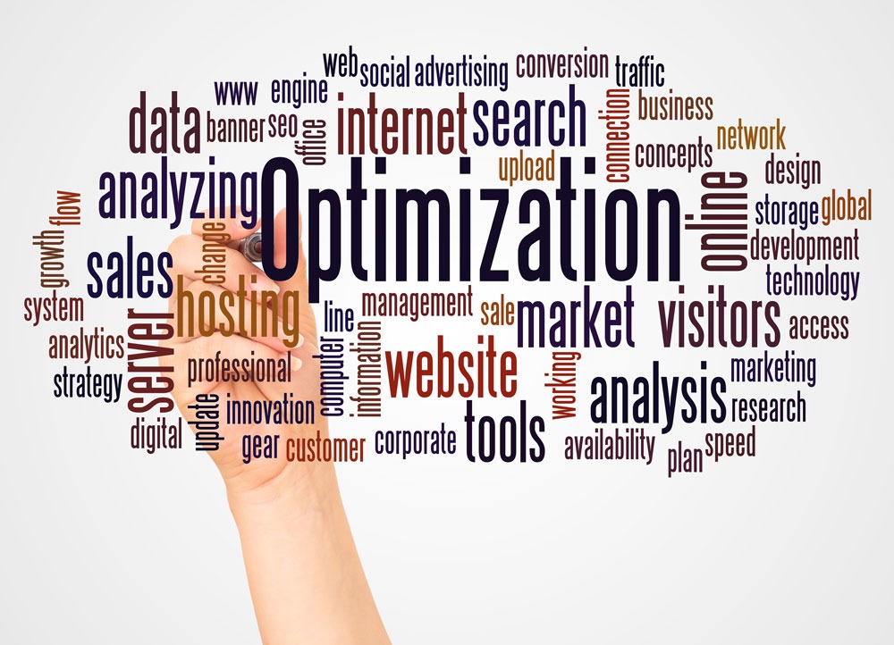 Hand writing the word "Optimization" surrounded by related keywords like "data," "website," "analytics," "internet," and "marketing," emphasizing SEO and digital marketing concepts.