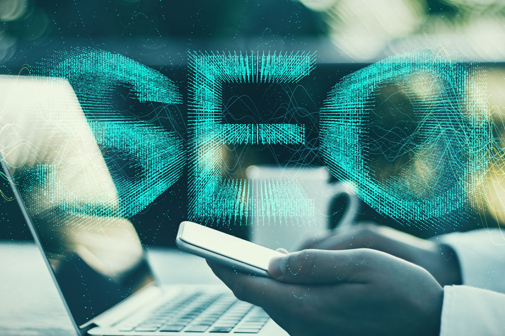 Person using smartphone and laptop with glowing "SEO" text overlay, symbolising digital marketing and search engine optimisation strategies.